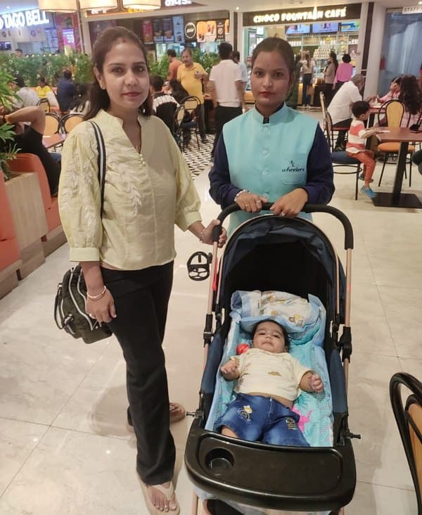 A Wheelerz attendant pushing a baby in a pram beside the parent